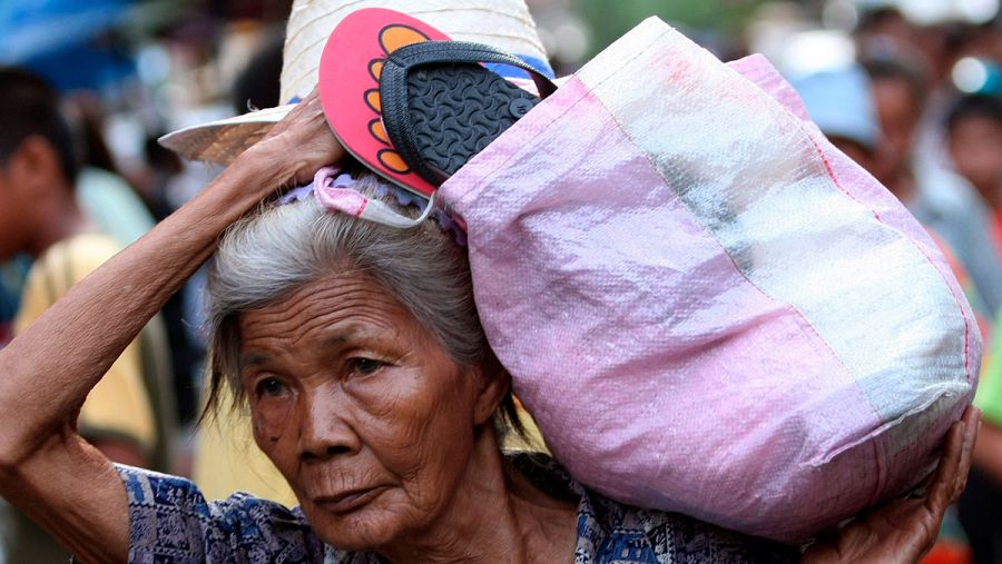 Una anciana tailandesa con una cesta en el hombro