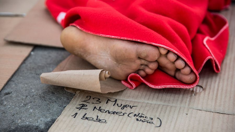 Un hombre duerme en el puerto de Algeciras después de ser rescatado por Salvamento Marítimo en el Estrecho de Gibraltar. Debajo de sus pies hay escrito un listado de las personas que Salvamento Marítimo salvó de una patera. © Olmo Calvo.
