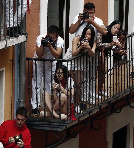 Un grupo de turistas orientales toman fotografías del encierro