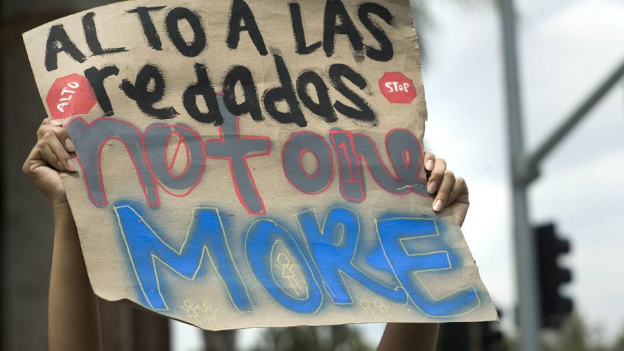 Una mujer sostiene un cartel en el que se puede leer: 