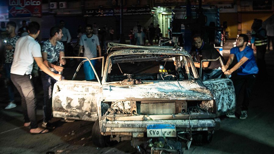 Varias personas rodean uno de los coches quemados en una explosión frente a un  hospital de El Cairo