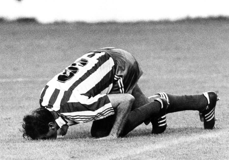 'Quini' besando el césped de El Molinón con la camiseta del Sporting.