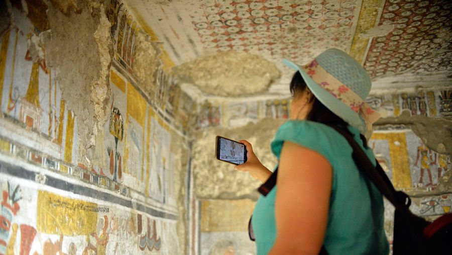 Una mujer saca una foto dentro de una de las tumbas inauguradas en Luxor