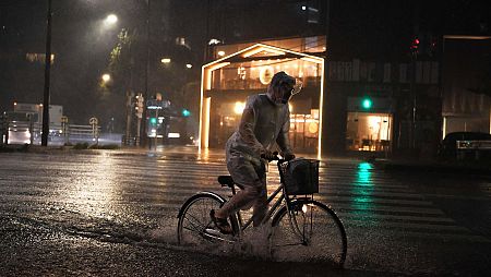 Un hombre viaja en bicleta en Tokio bajo una fuerte lluvia