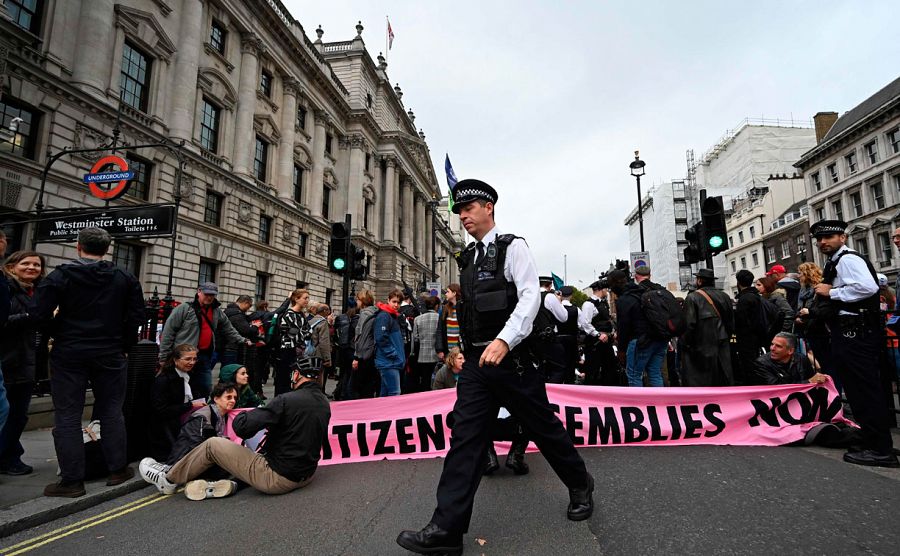 Oficiales de policía británicos hablan con varios activistas del cambio climático del grupo Extinction Rebellion mientras bloquean el cruce de las calles Whitehall y Parliament Square en el centro de Londres