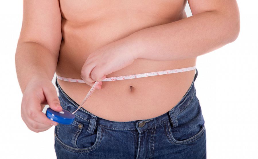 Un niño mide la circunferencia de su cintura.