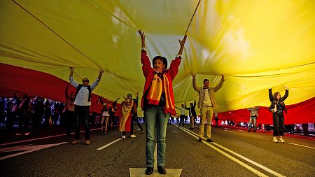 Decenas de personas sostienen una enorme bandera de España en el acto de Vox en la plaza de Colón