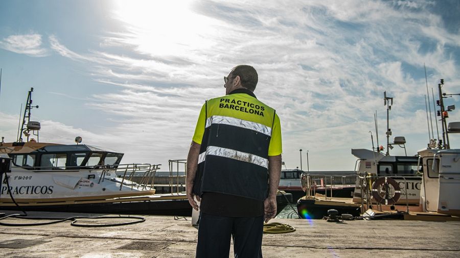 Un pràctic del Port de Barcelona d'esquenes mirant el moll amb diversos vaixells