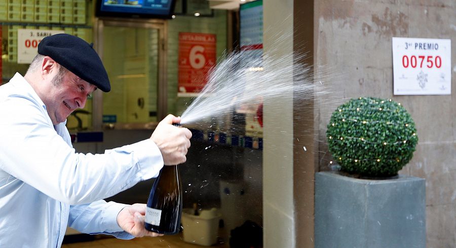 Tercer premio de la lotería de Navidad 2019: El lotero de la administración 23 de Bilbao abre una botella para celebrar el reparto del tercer premio