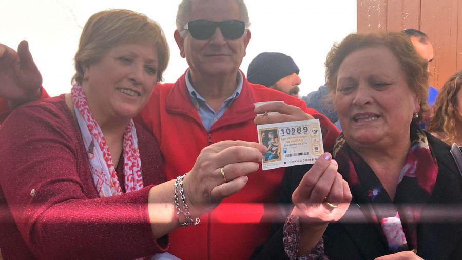 Genoveva Calle y Victoria Pecero sostienen el décimo premiado con el segundo premio de la Lotería de Navidad en Fuente del Maestre