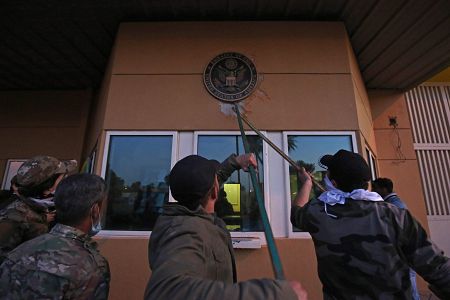 Manifestantes arrancan una placa de la entrada de la Embajada de EE.UU. en Bagdad (Irak).