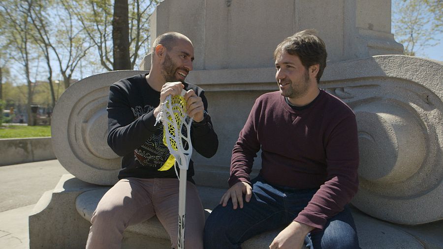 L'Ander Mirambell i el Pol asseguts en un banc amb una xarxa de Lacrosse.