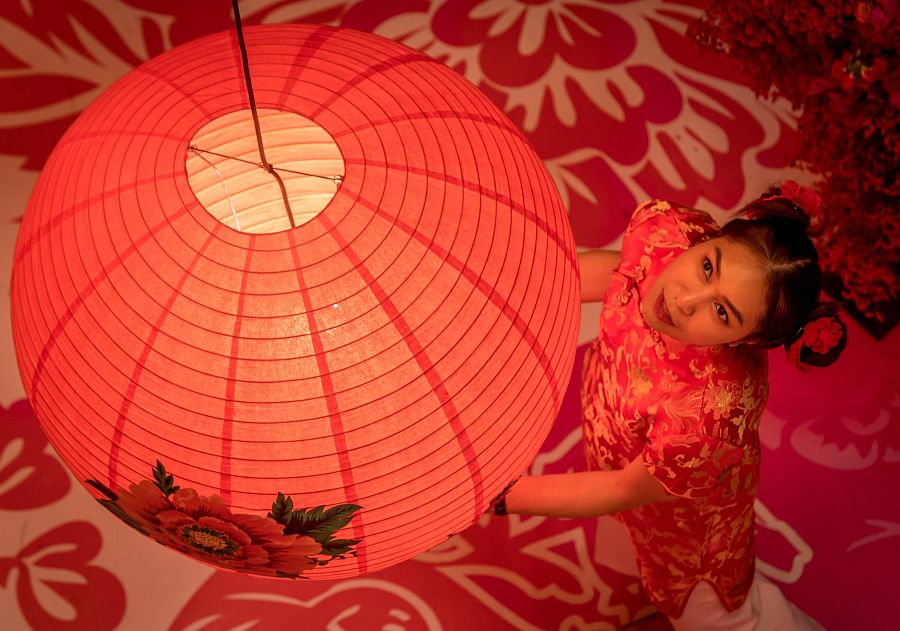Una mujer con un traje típico posa en una tienda decorada para el nuevo año