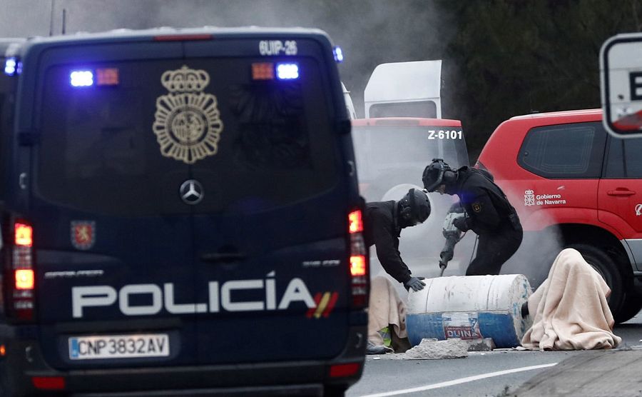 Efectivos de la Policía Nacional tratan de liberar a un grupo de personas que se han encadenado con bidones de hormigón en Pamplona, durante la jornada de huelga.