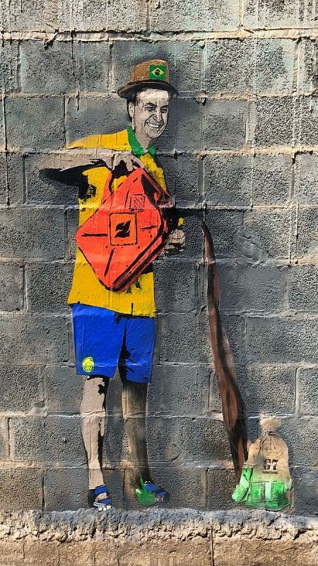 En la imagen, Bolsonaro, con una gorra con la bandera de Brasil, echa gasolina a La Amazonia.