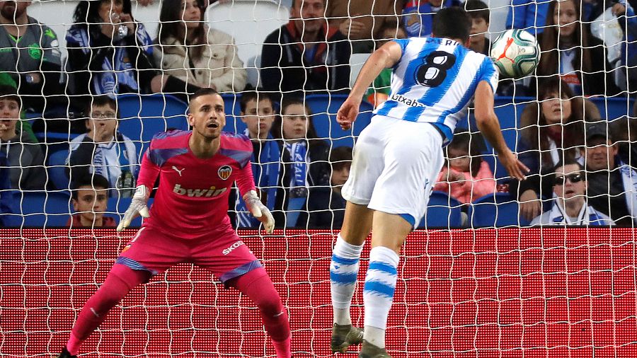 El centrocampista Mikel Merino (d) de la Real Sociedad marca un gol ante el guardameta del Valencia.