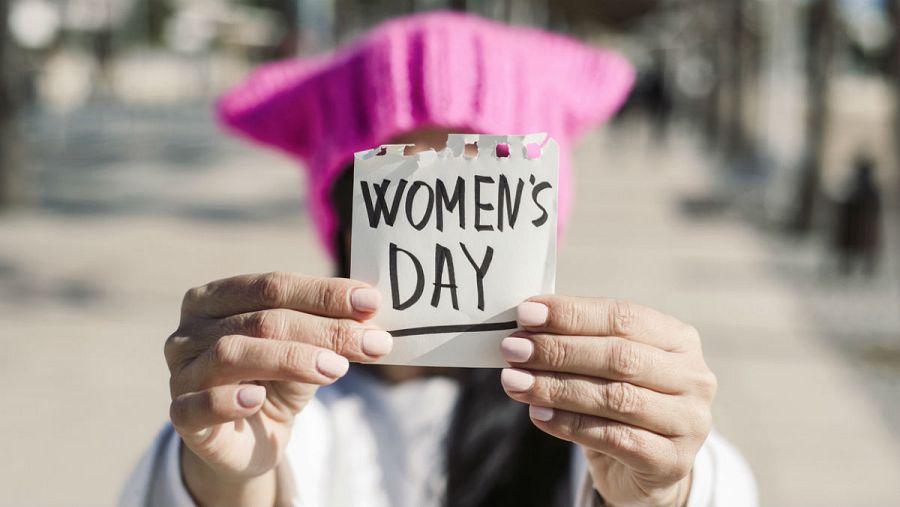 Plano detalle de una mujer sosteniendo un papel en el que se puede leer 