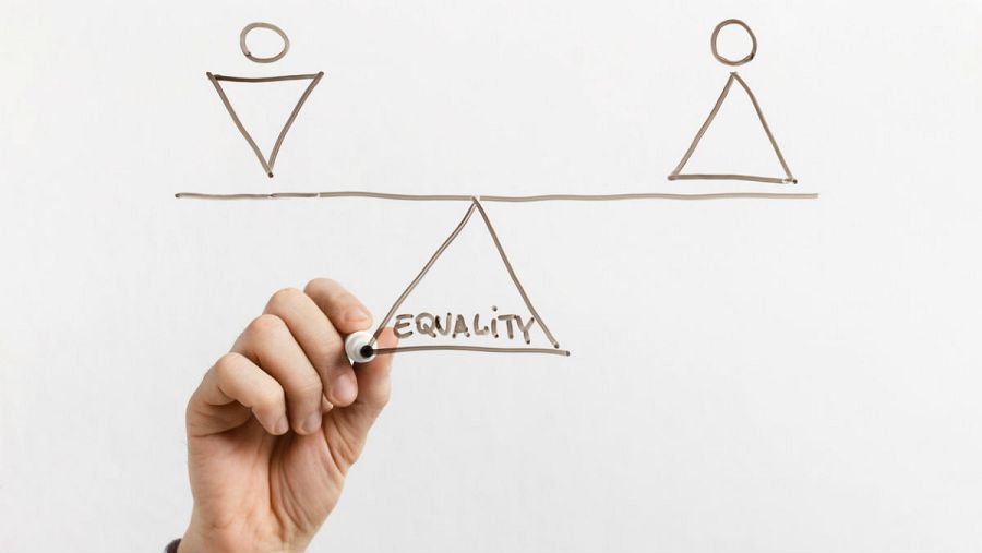 En la imagen, una persona dibuja una balanza que ejemplifica la búsqueda de la igualdad entre hombres y mujeres.