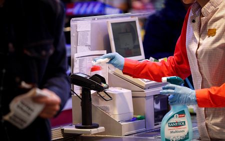 Una cajera desinfecta el datáfono entre el paso de cada cliente en un supermercado de San Sebastián.