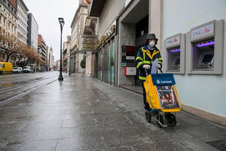 Una trabajadora del servicio de Correos realiza su trabajo por las calles casi desiertas de Zaragoza.