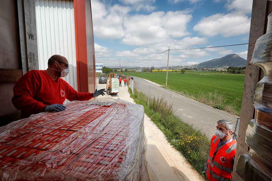 Voluntarios de la Cruz Roja descargan alimentos en el aeródromo de Igualada-Ódena (Barcelona), donde se instalará un espacio logístico humanitario para distribuir productos de primera necesidad entre las familias en riesgo afectadas por el confinamie