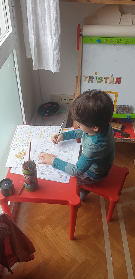 Un niño juega junto a la ventana en su quinta semana de confinamiento