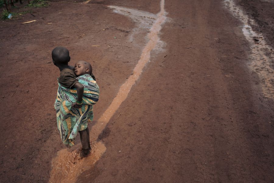 Dos niños caminan sobre charcos de lluvia en el campo de Rho.