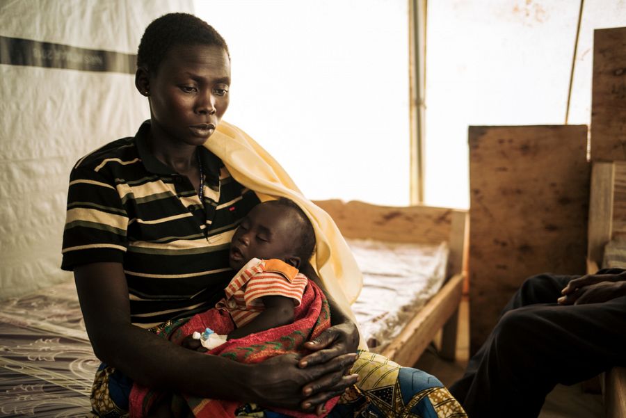 Honorine, de 31 años, sostiene a su hija de 7 meses en la clínica móvil en el campo de desplazados de Rho.