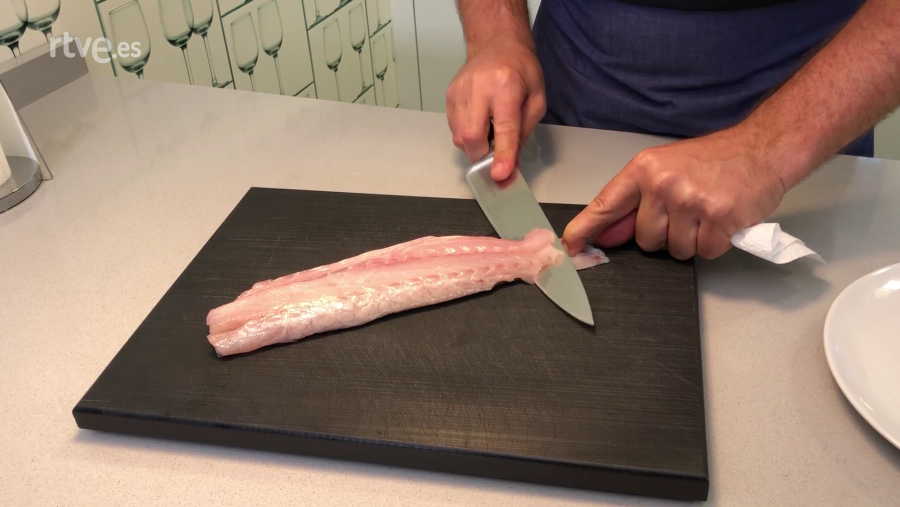 Con ayuda de papel higiénico y el cuchillo en diagonal, retiramos la piel del pescado
