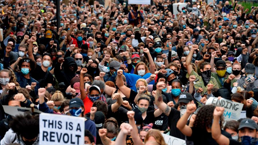 Los manifestantes se arrodillan y levantan los puños en un minuto de silencio por George Floyd y otras víctimas de la brutalidad policial y el racismo frente a una comisaría en Boston