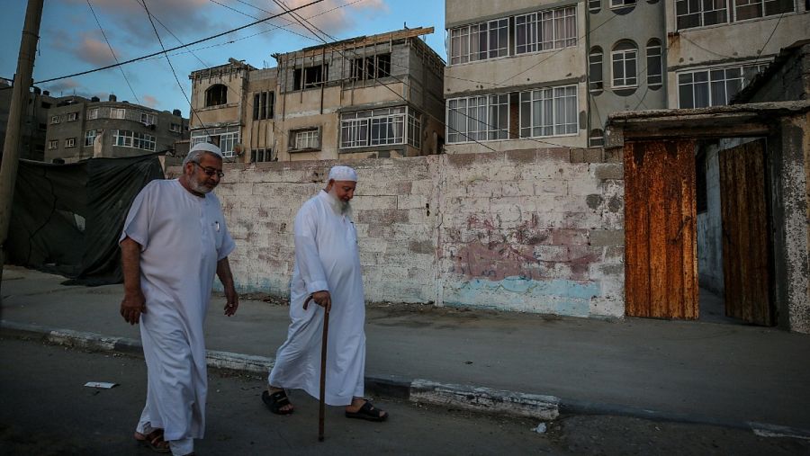 Dos ancianos palestinos caminan por una calle del campamento de refugiados de Al Shatea, en medio de la actual pandemia del coronavirus COVID-19 en la ciudad de Gaza.