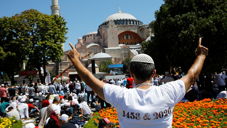 Un hombre hace un gesto de alegría mientras la gente espera el comienzo de las oraciones del viernes fuera de la Gran Mezquita de Santa Sophia, por primera vez después de que una vez más fuera declarada mezquita después de 86 años, en Estambul, Turqu