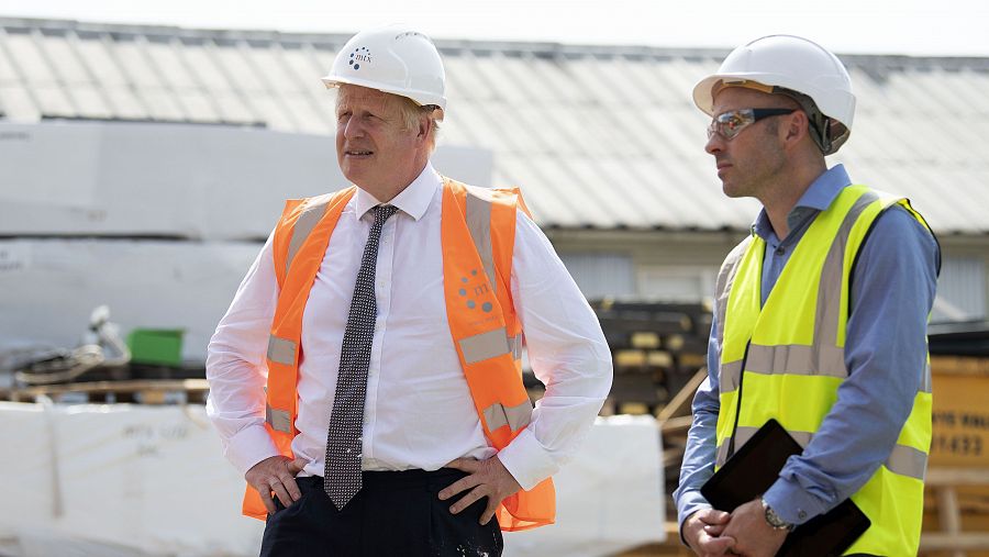 Boris Johnson, primer ministro del Reino Unido, junto a un obrero con gesto de preocupación