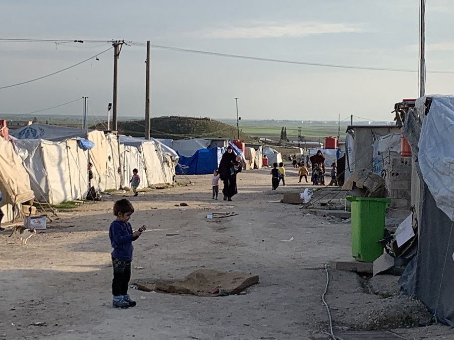 Unos niños caminan entre las tiendas del campo de Roj