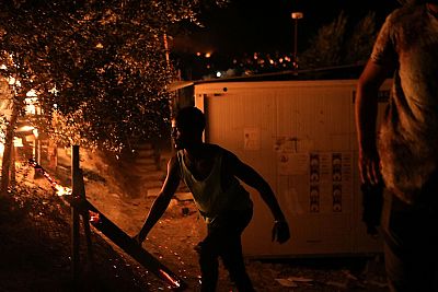 Un migrante mueve un tronco ardiendo en el campamento de Moria