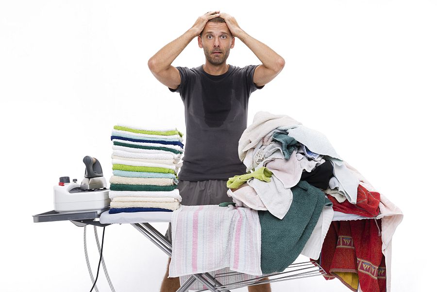 Desperate man with hands in his hair behind an ironing board
