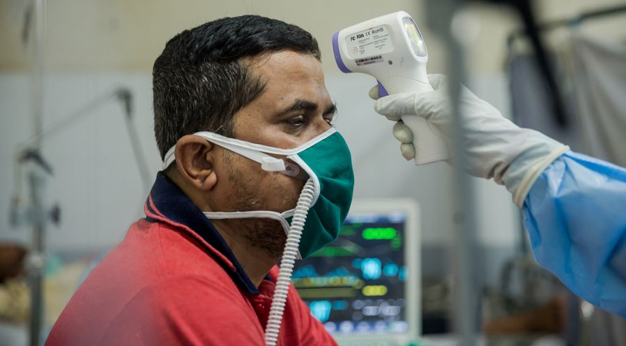 El Dr. Ilham toma la temperatura a un paciente ingresado en la unidad de pacientes de COVID-19.
