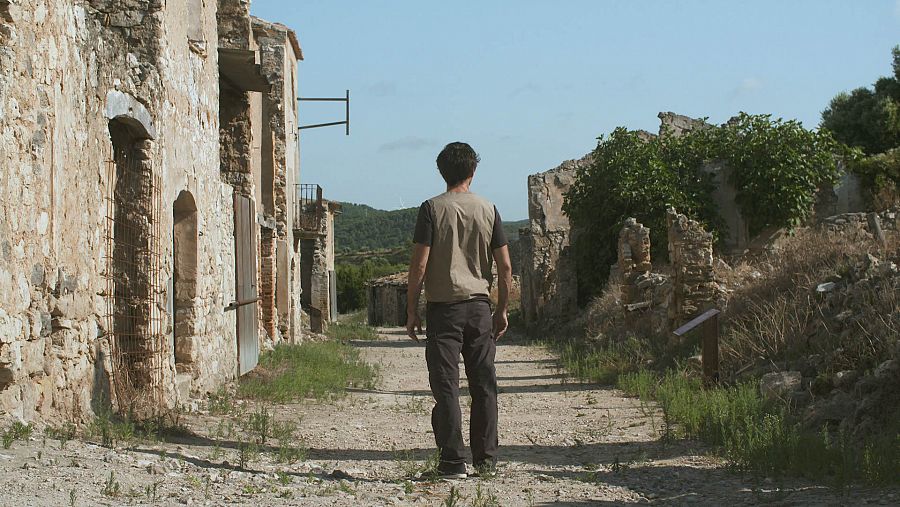 Bruno Oro passejant per un carrer d'un poble abandonat