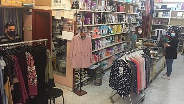 Carlos y Gema, mientras atienden a una clienta en su tienda de confecciones.