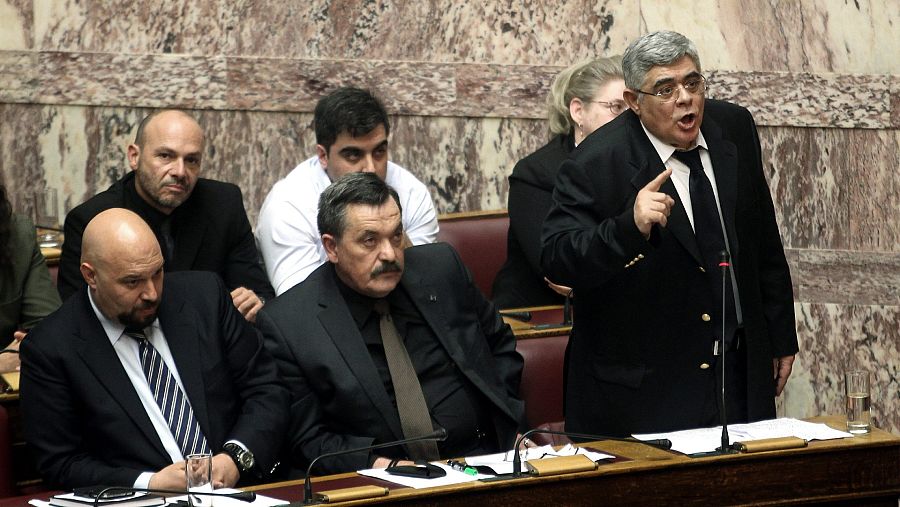 El líder del partido neonazi, Nikos Michaloliakos (d) durante una sesión plenaria del parlamento (Foto archivo)