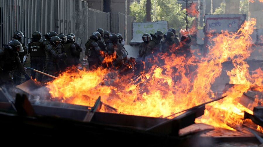 Agentes de la policía antidisturbios junto a una barricada en llamas durante una protesta contra el gobierno de Chile en Santiago, Chile.