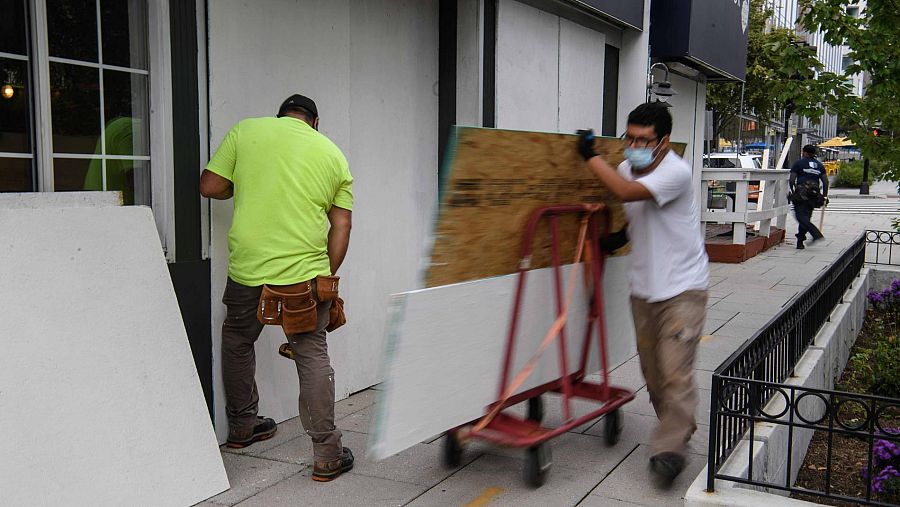 Dos operarios instalan paneles protectores en un establecimiento de Washington, antes de las elecciones de EE.UU.