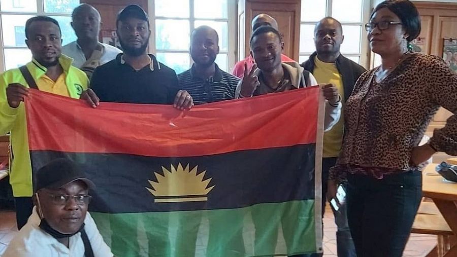 Kingsley sostiene la bandera de Biafra junto a un grupo de amigos.