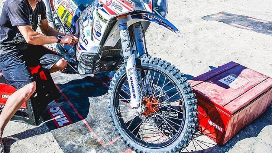 Imagen de un participante en el Dakar reparando su moto.