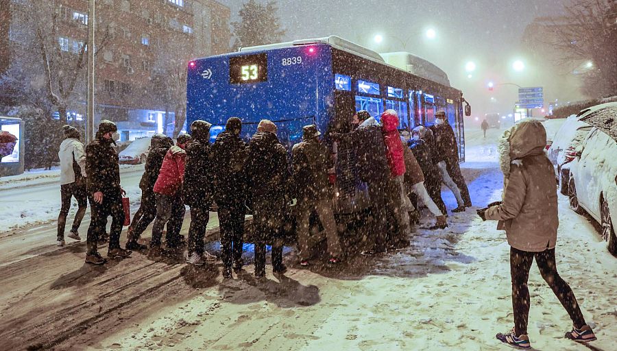 Varias personas empujan un autobús bajo una intensa nevada en la avenida Ramón y Cajal