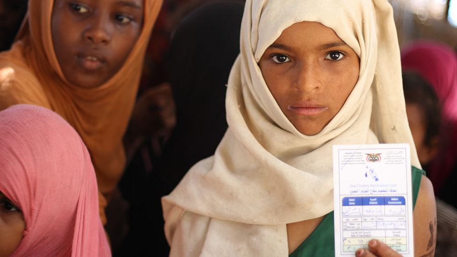 Una niña yemení muestra su cartilla de vacunación.