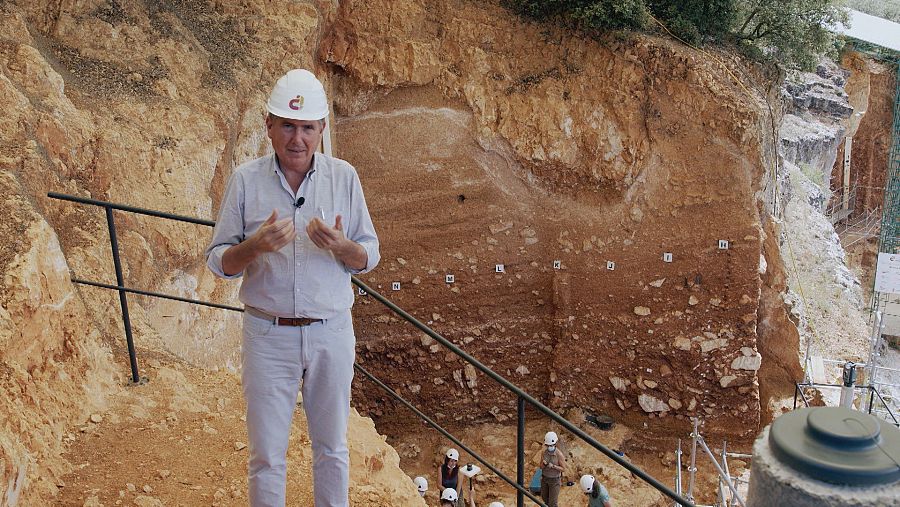 Manuel Pimentel en Atapuerca, ante luna pared de capas de sedimentos