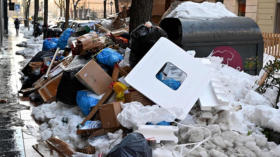 Bolsas de basura se amontonan alrededor de los contenedores en una calle de Madrid.