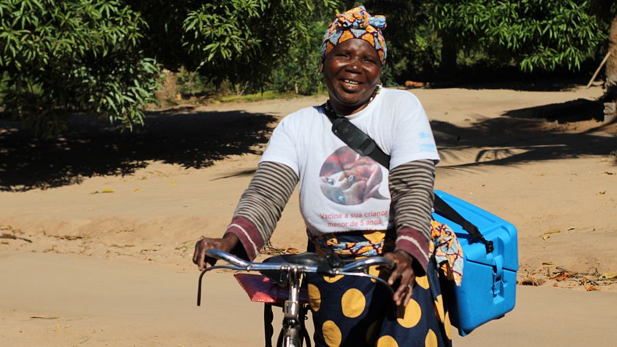 Una sanitaria transporta en su bicicleta una nevera portátil con las vacunas para los niños.