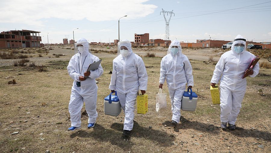 Los vacunadores están ocultos bajo trajes de seguridad contra la COVID-19.